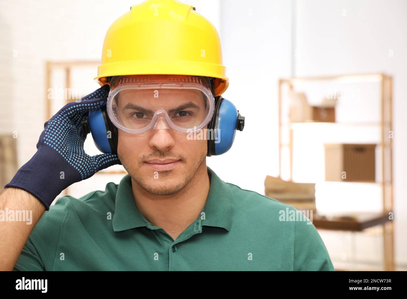 Worker wearing safety headphones indoors. Hearing protection device