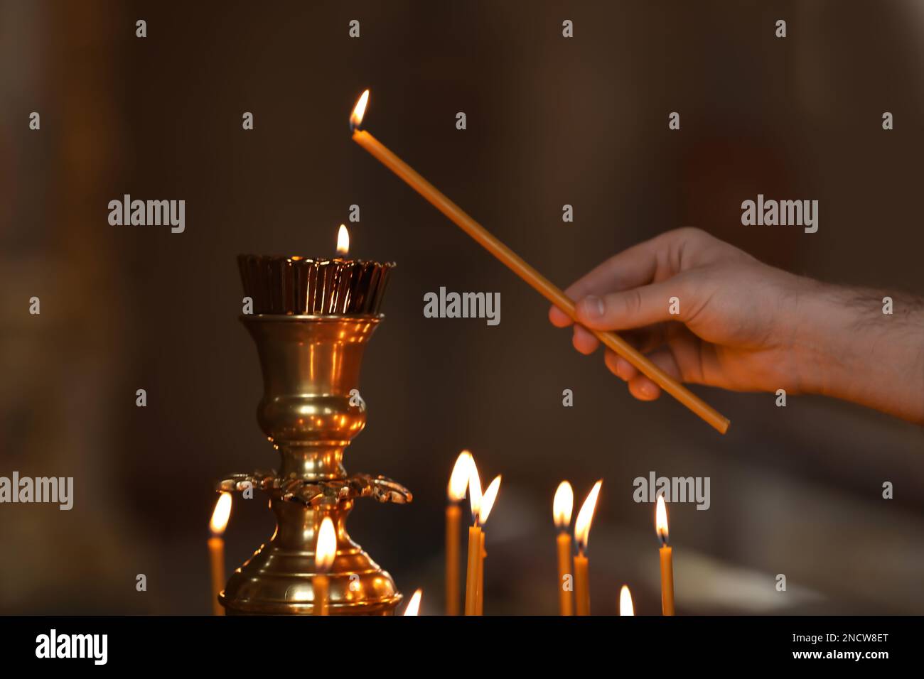 Man lighting candle near stand in church, closeup. Baptism ceremony Stock Photo Alamy