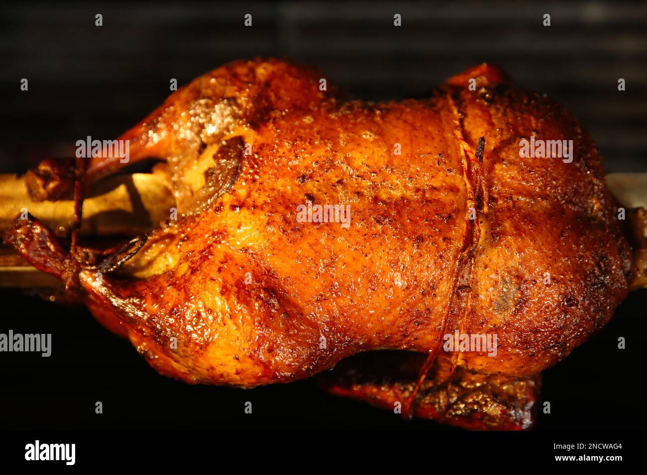 Grilling whole delicious duck in rotisserie machine, closeup Stock