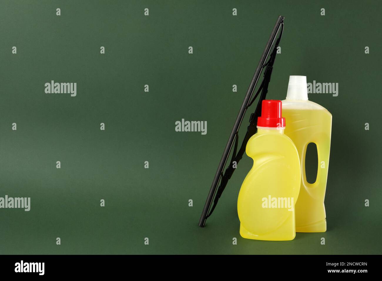 Bottles of windshield washer fluids and wiper on dark green background