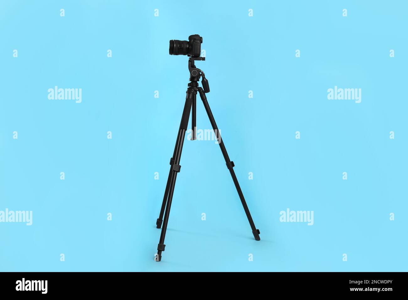 Modern tripod with professional camera on light blue background Stock ...