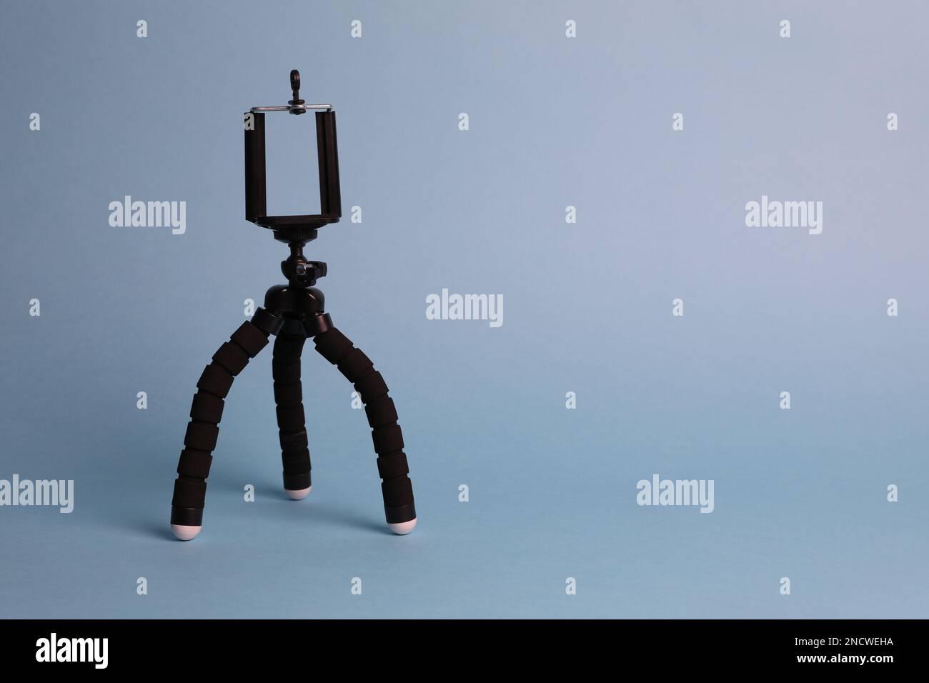 Modern stylish mobile tripod on light blue background. Space for text ...
