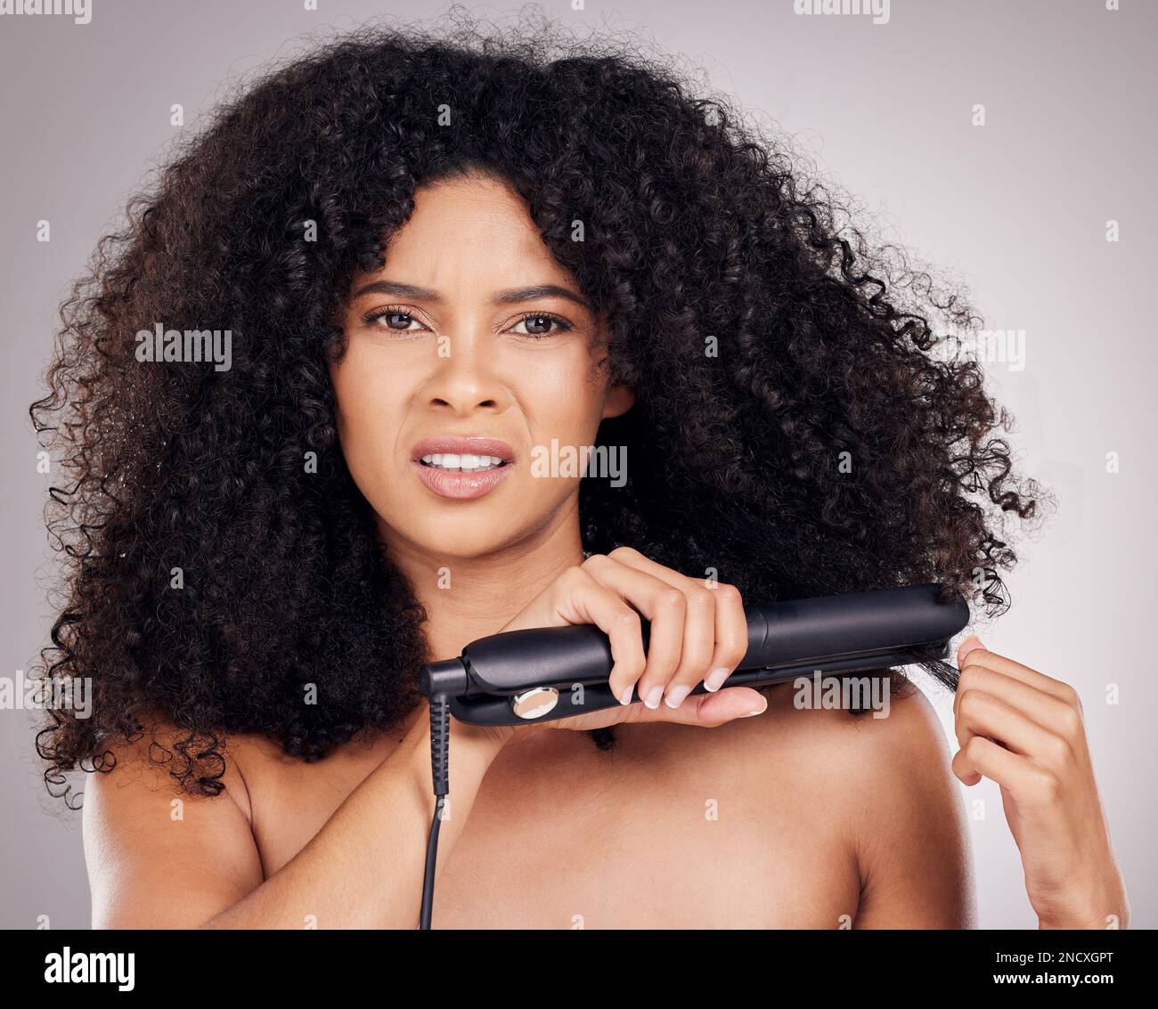 Face portrait, sad and woman with hair straightener in studio isolated on gray background. Haircare damage, hairloss and black female model angry with Stock Photo