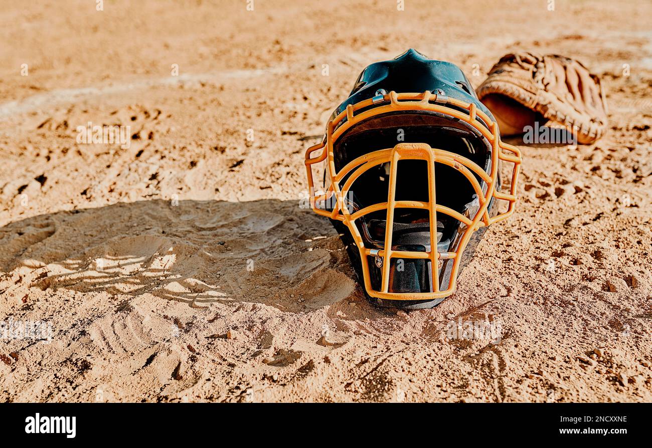 A game of baseball can fix any mood. a catchers helmet lying on a baseball field. Stock Photo