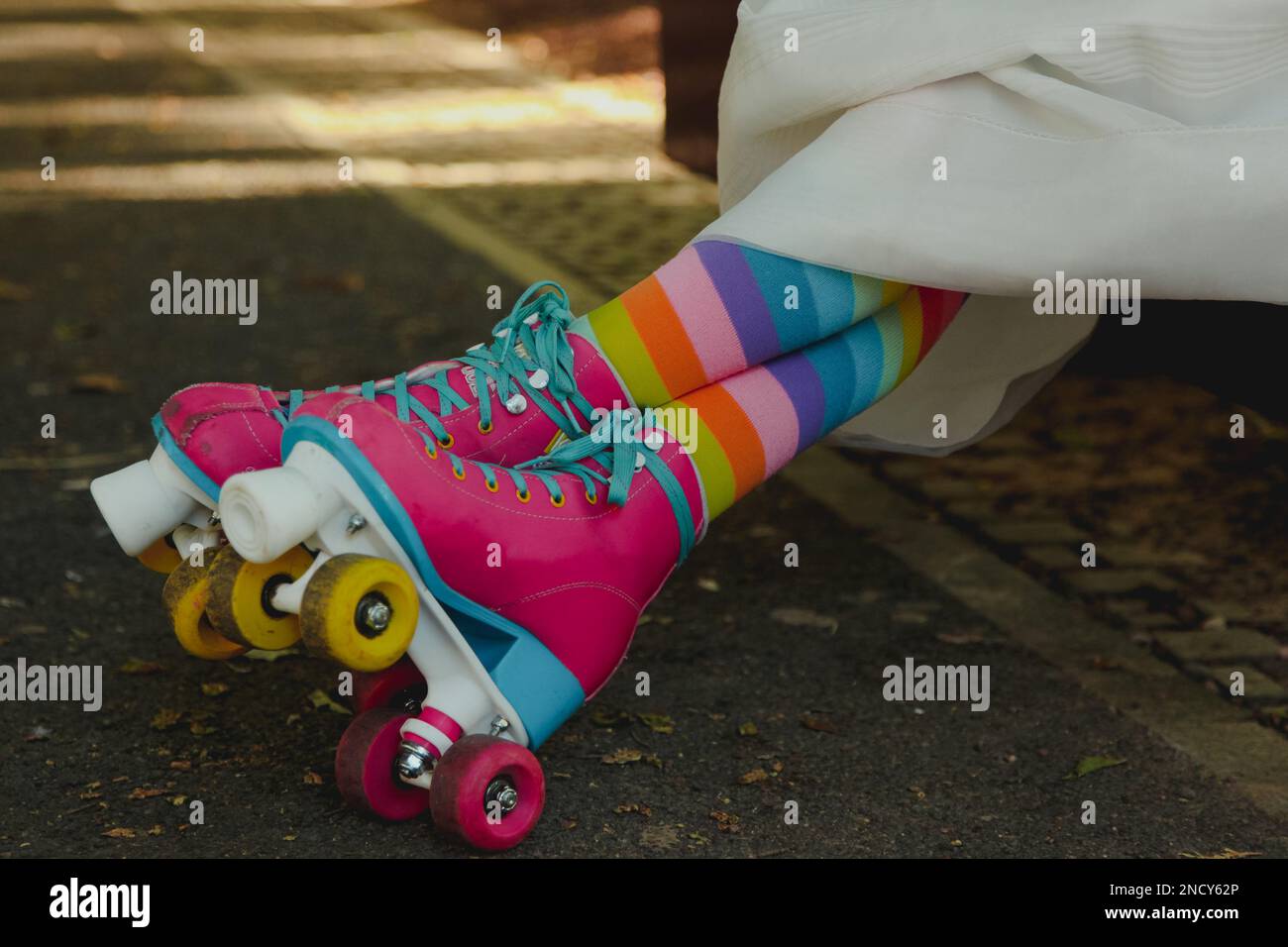 Close-up of a woman in a wedding dress wearing multi coloured long socks and rollerskates Stock Photo