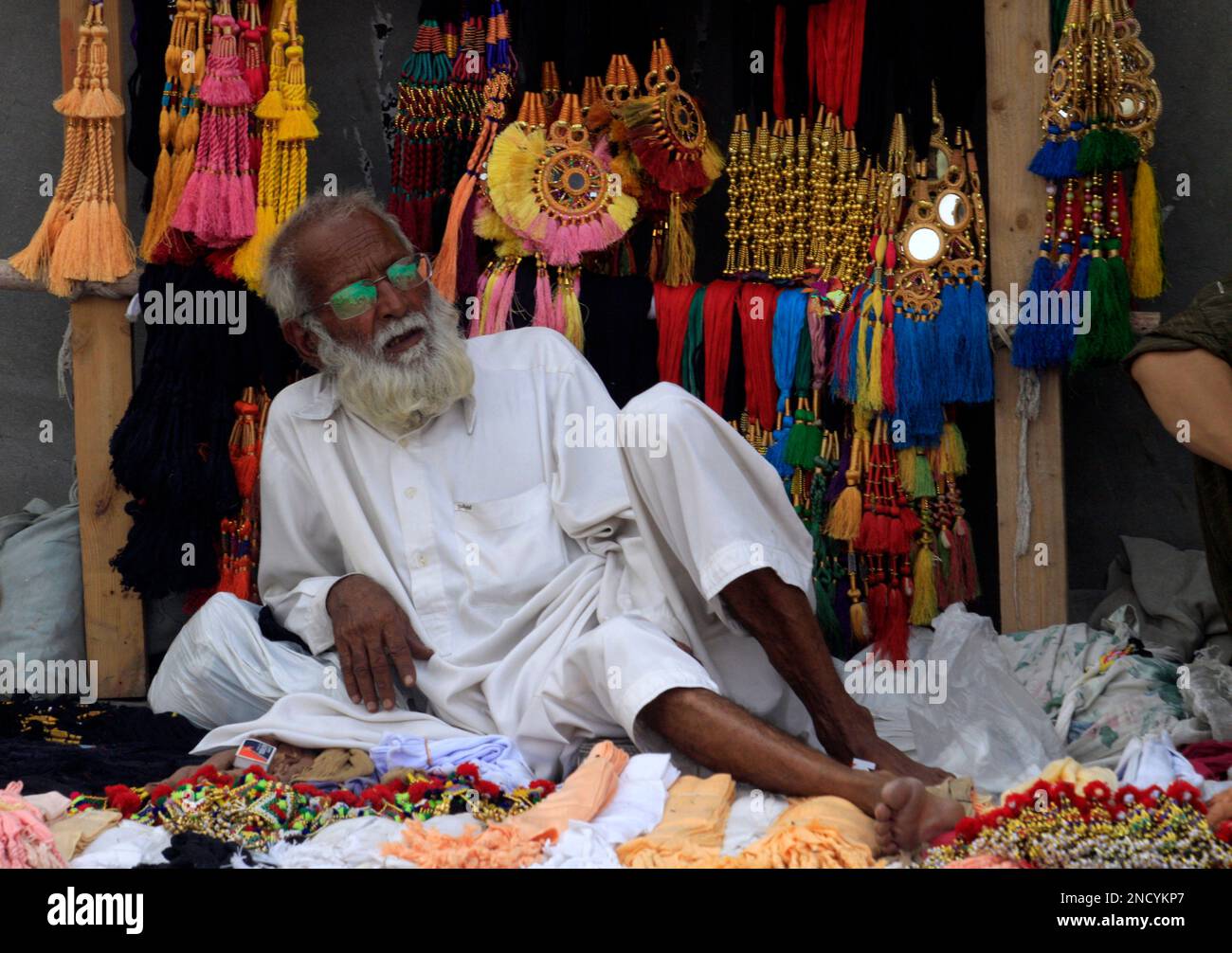 A Pakistani man waits for customers selling traditional long ornamental ...