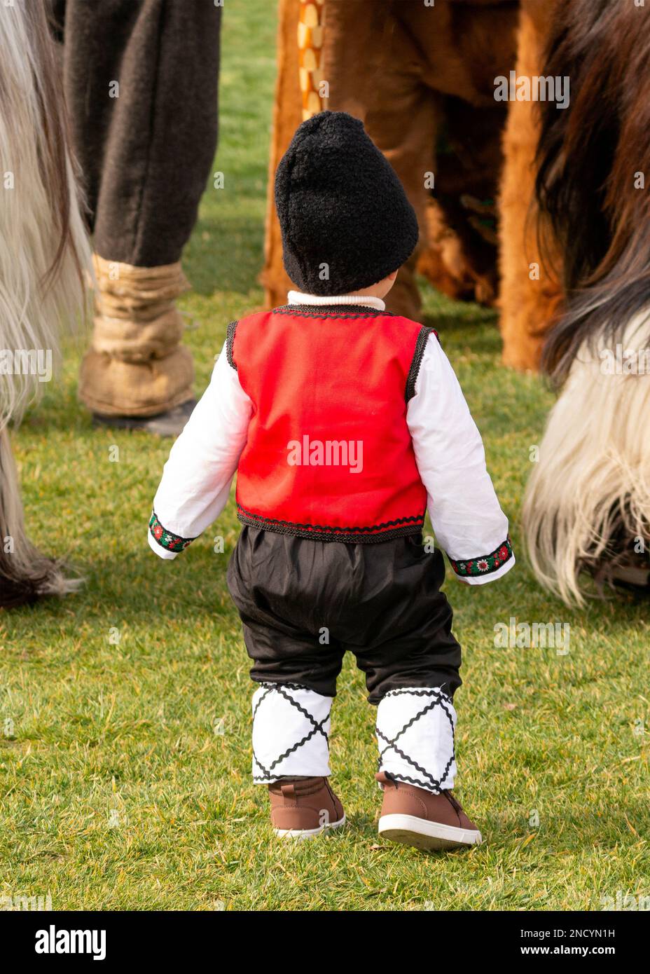 Little boy in folklore outfit among Kukeri dancers at the annual Simitlia winter festival in Simitli, Blagoevgrad County, Bulgaria Stock Photo