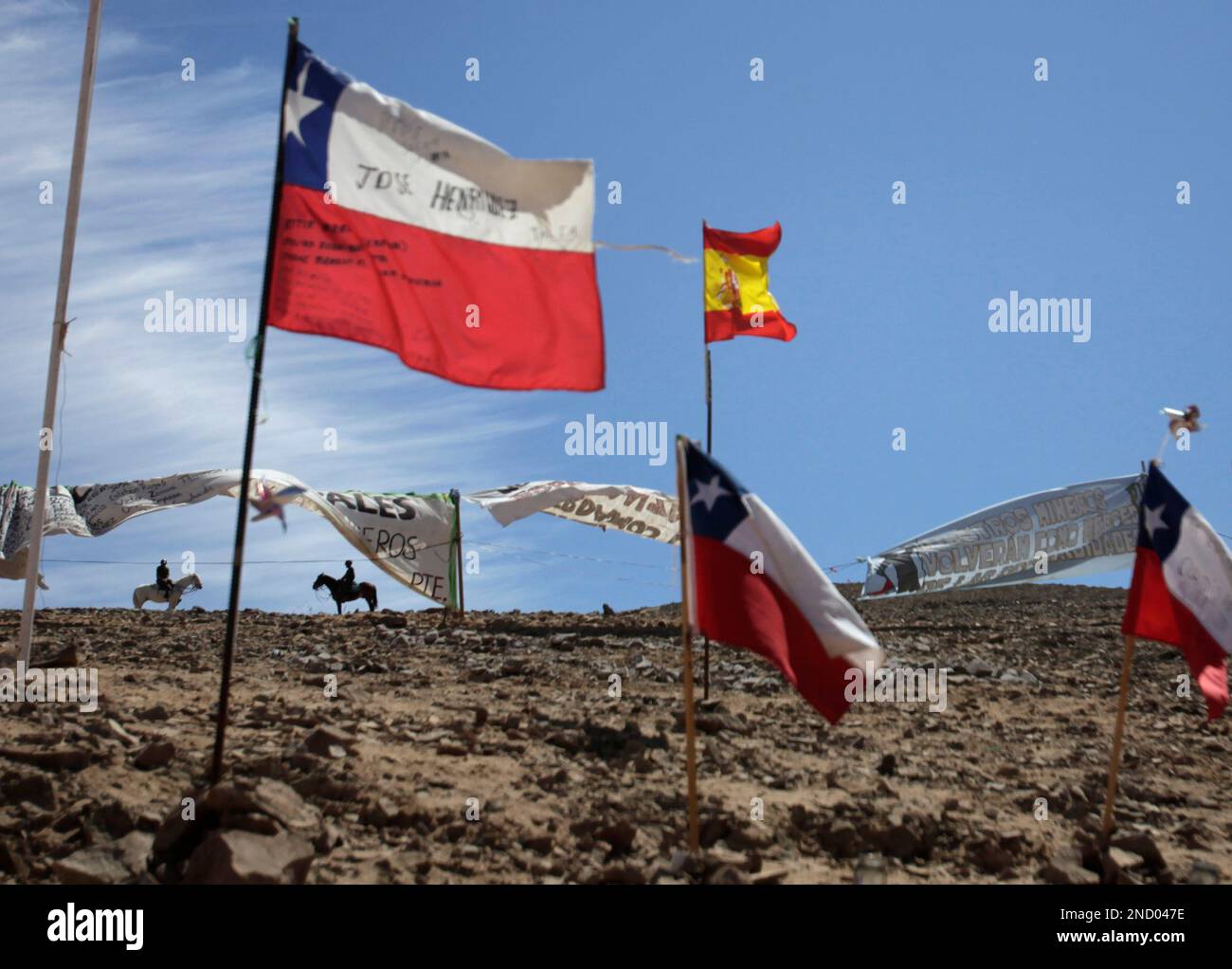 Police on horseback patrol near Chilean flags and a Spanish flag flying at  the San Jose Mine near Copiapo, Chile, Tuesday Oct. 5, 2010. Chile's  President Sebastian Pinera announced that his government