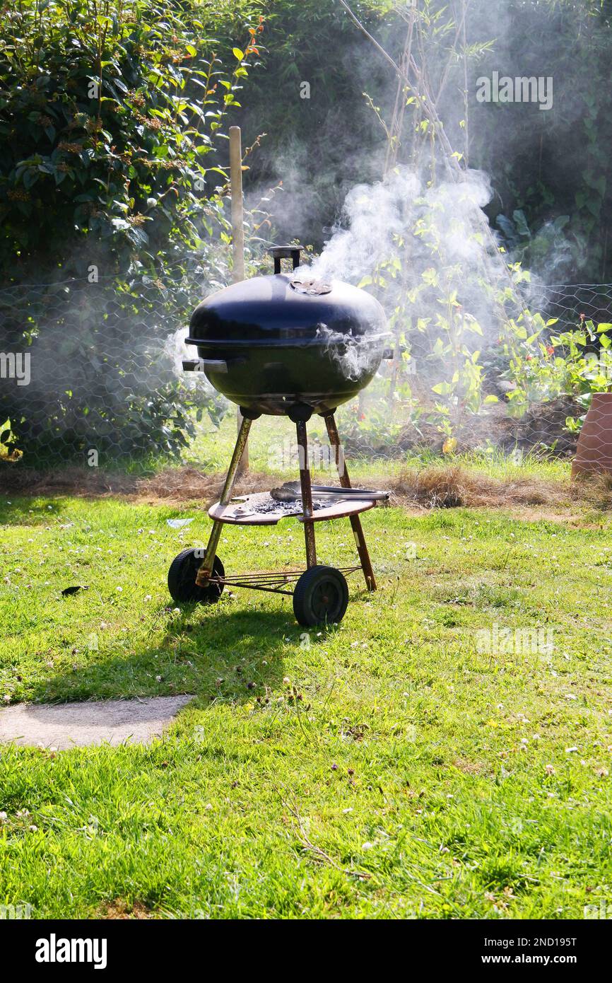 Smoking hot kettle type barbecue in a garden setting John Gollop Stock Photo Alamy