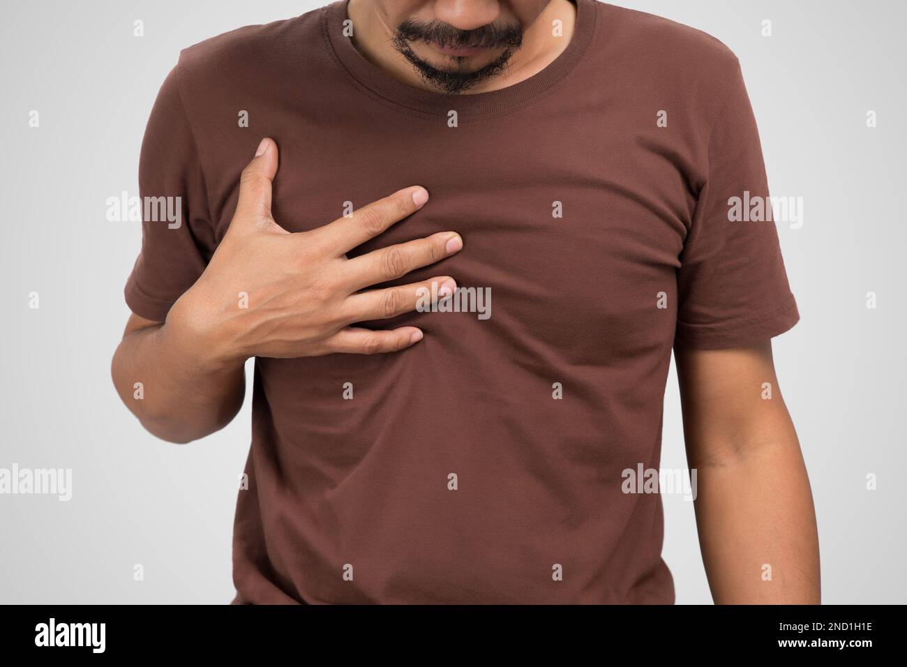Asian man suffering from gastritis on gray background. Stock Photo