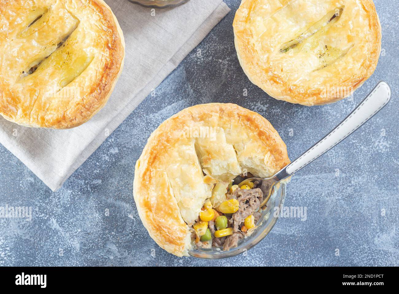 Small beef pot pies or deep dish pies in ramekin, crust broken open to