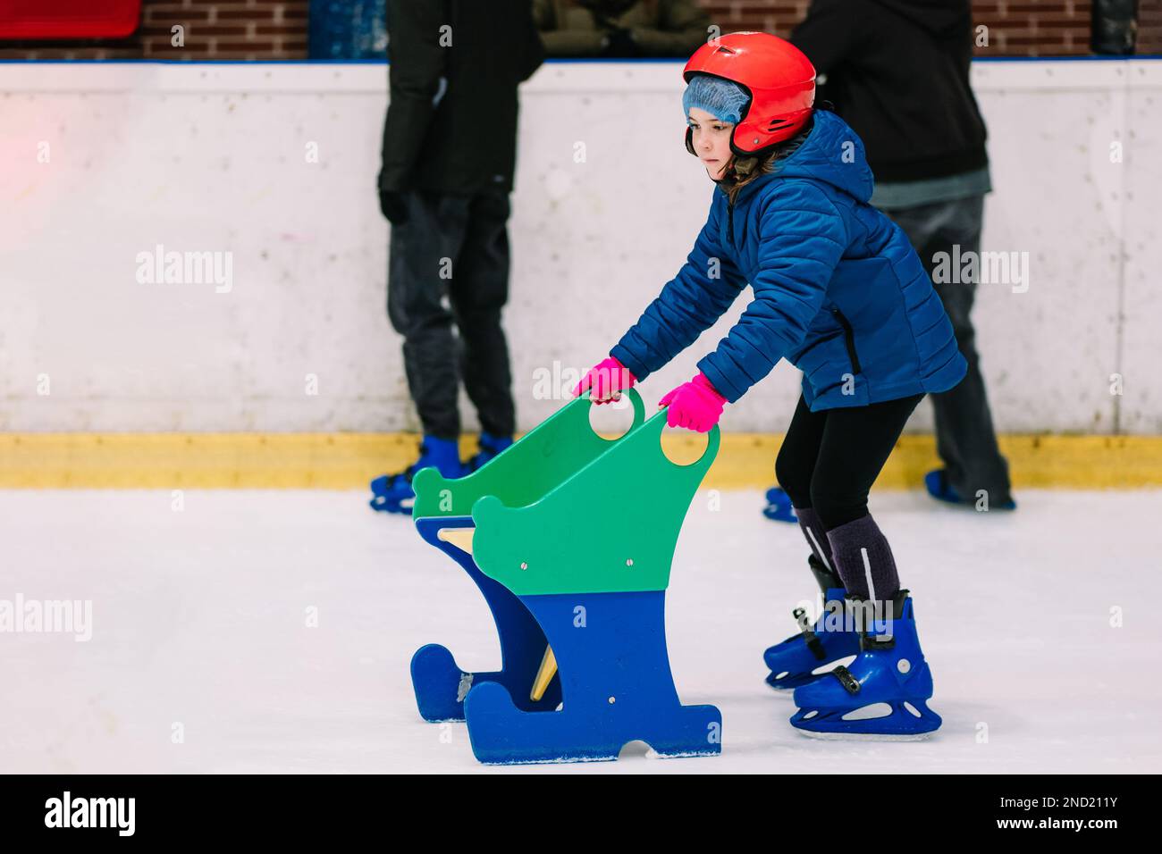 Calm girl in warm clothes and protective helmet learning ice skating