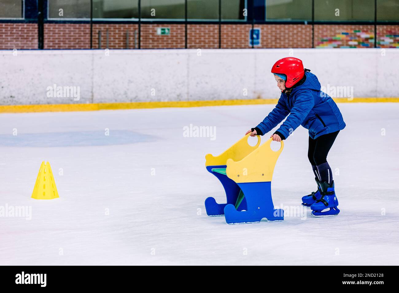 Calm girl in warm clothes and protective helmet learning ice skating