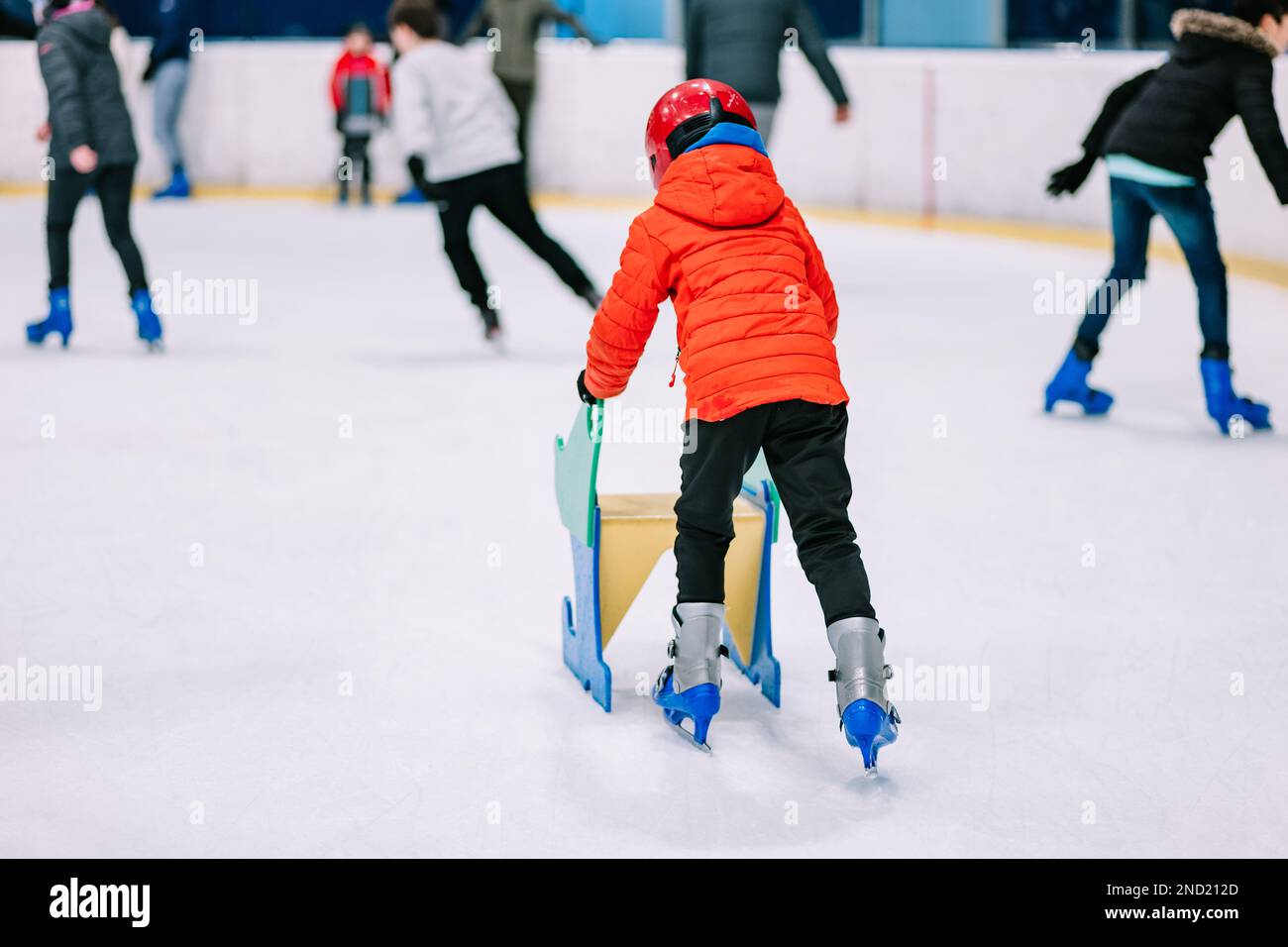 Back view boy in warm clothes and protective helmet learning ice