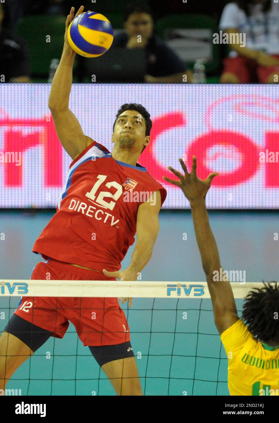 Hector Soto, left, of Puerto Rico, hits past the Dominican Republic defense during their semifinal match in the volleyball competition of the Central American and Caribbean Games in Cartagena, Colombia, Friday, July