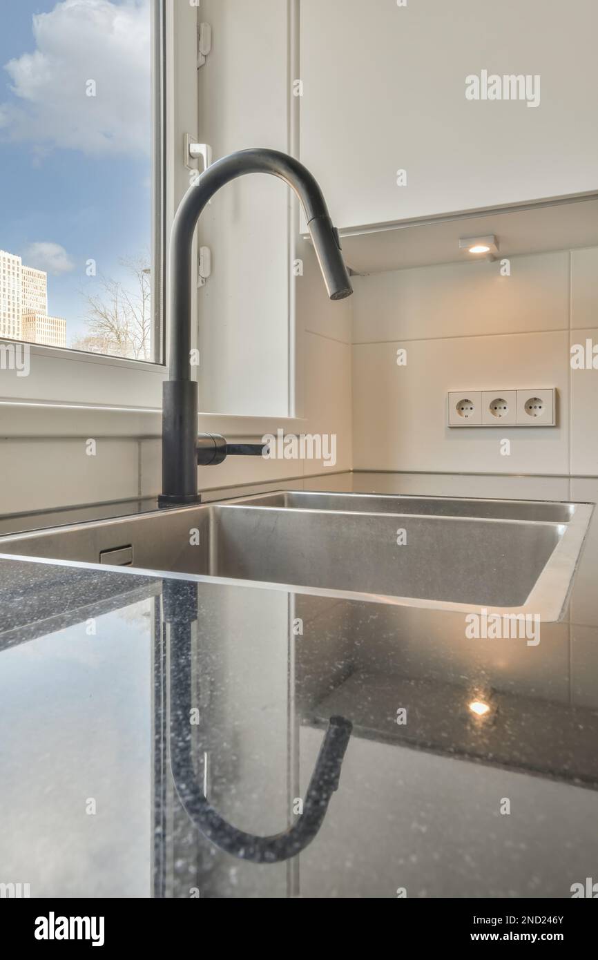 Contemporary kitchen with black faucet marble counter near window and