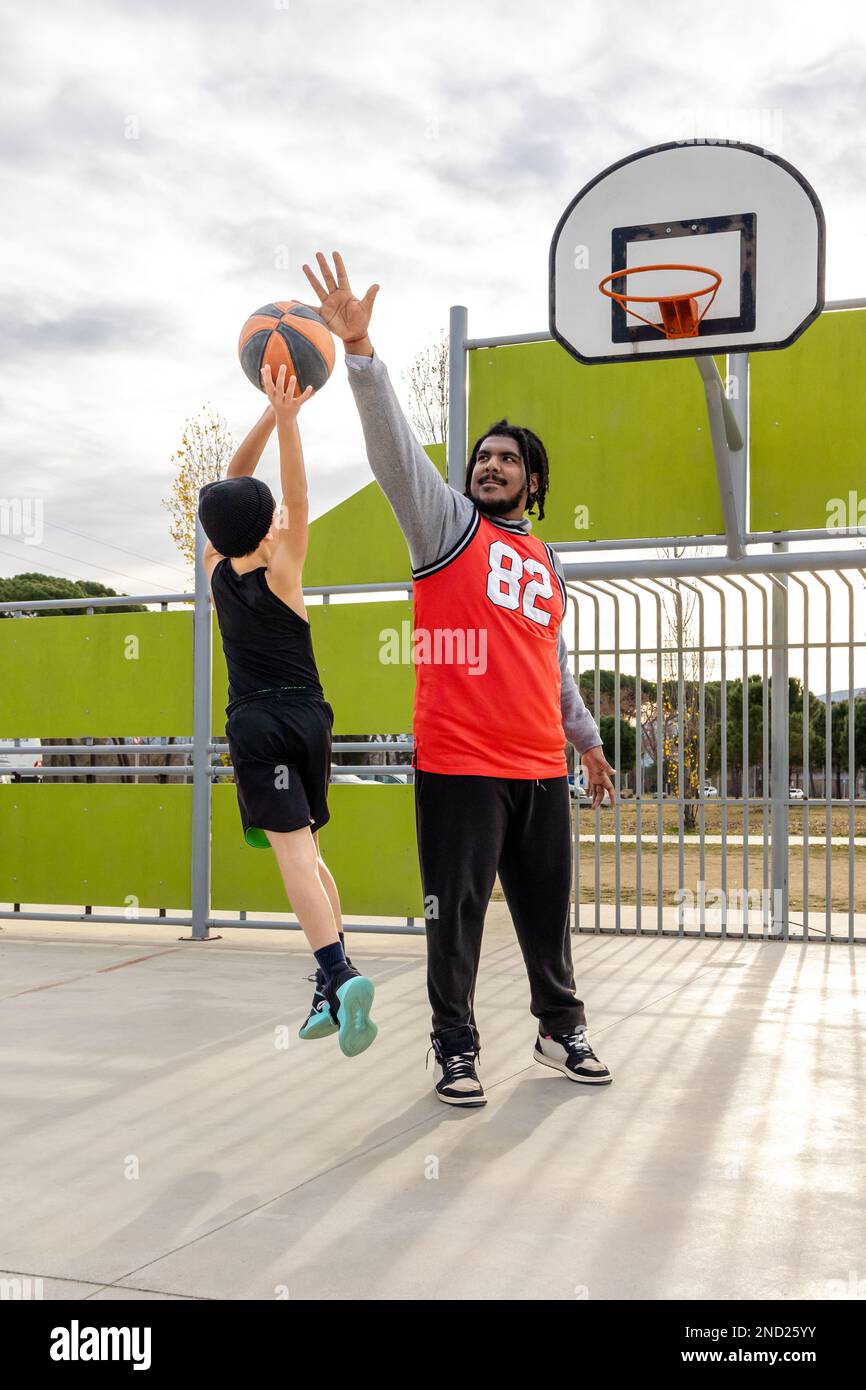 Full body of determined kid throwing ball into hoop while playing