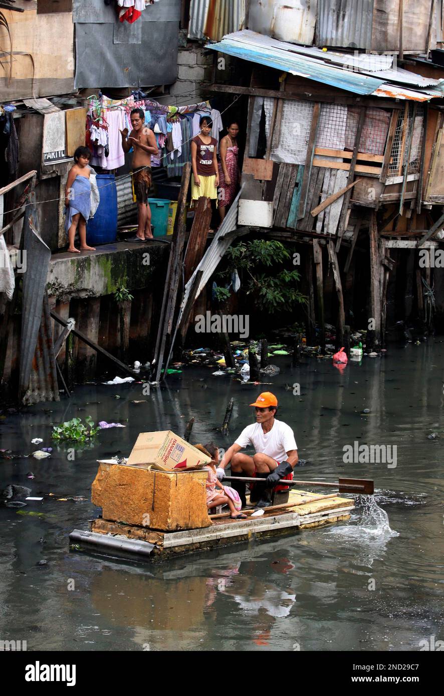 A man paddles his improvised raft with her daughter as he collects ...