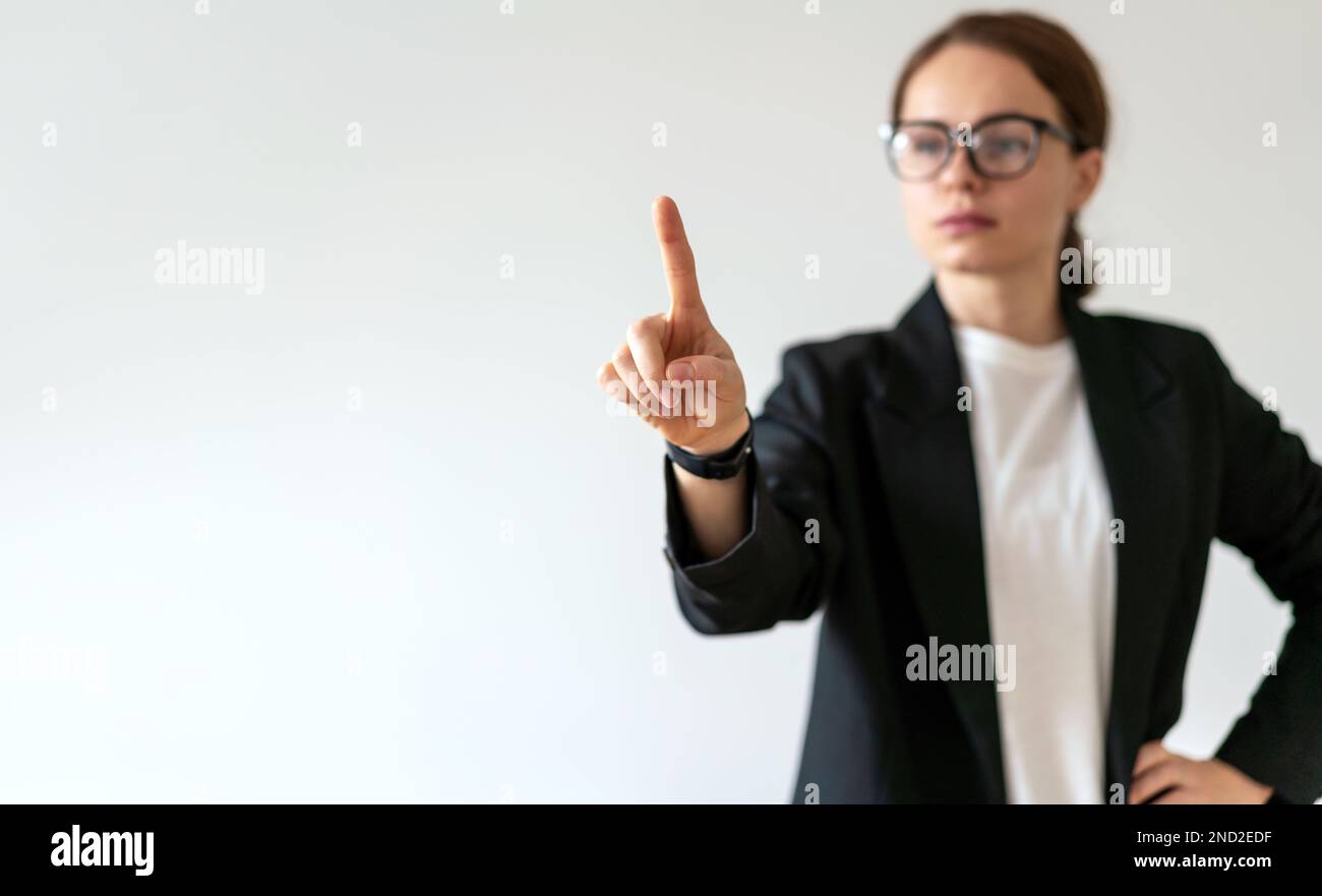 Young adult woman in glasses touching virtual interface, infographic, screen with her hand. Stock Photo