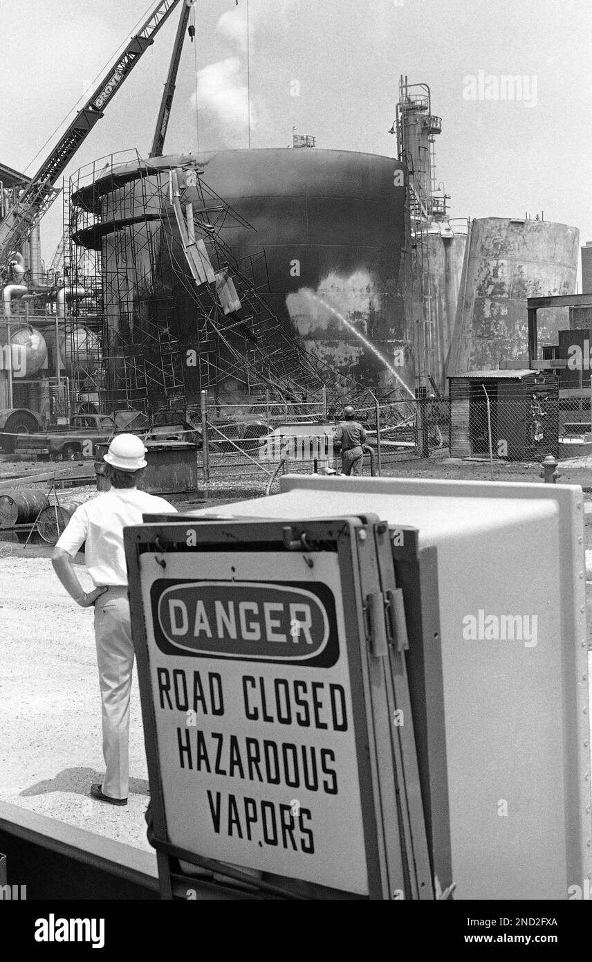 A danger sign on the back of a truck sits near charred tanks at the