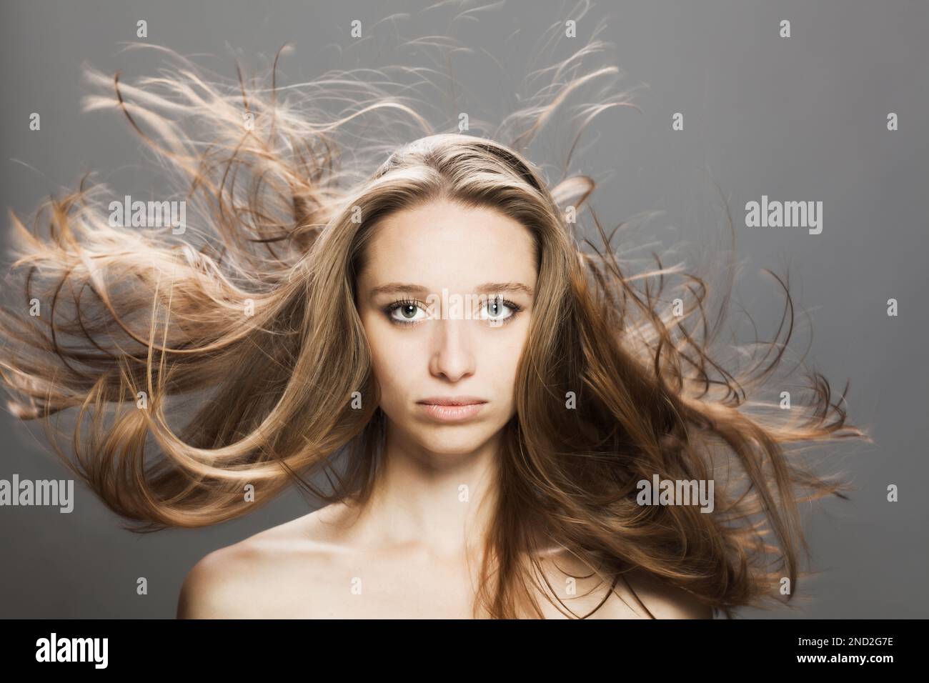 girl with flowing hair in the air studio portrait against gray