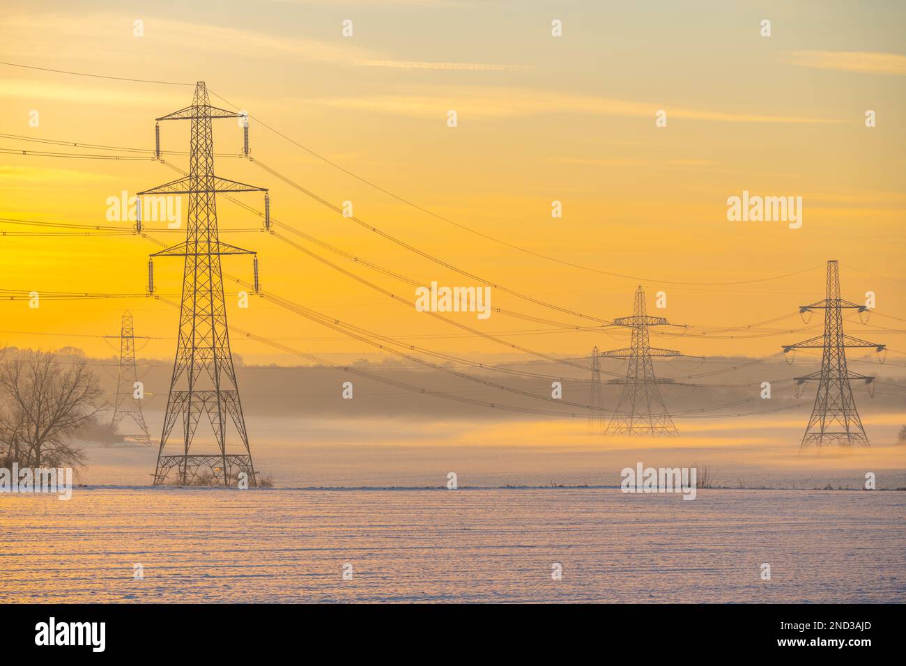 Power lines above snow covered fields at sunset near Ifield, Gravesend Kent Stock Photo