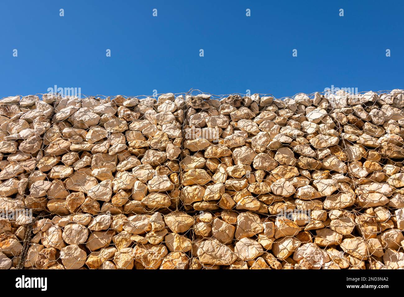 Gabion stone wall with blue sky background Stock Photo