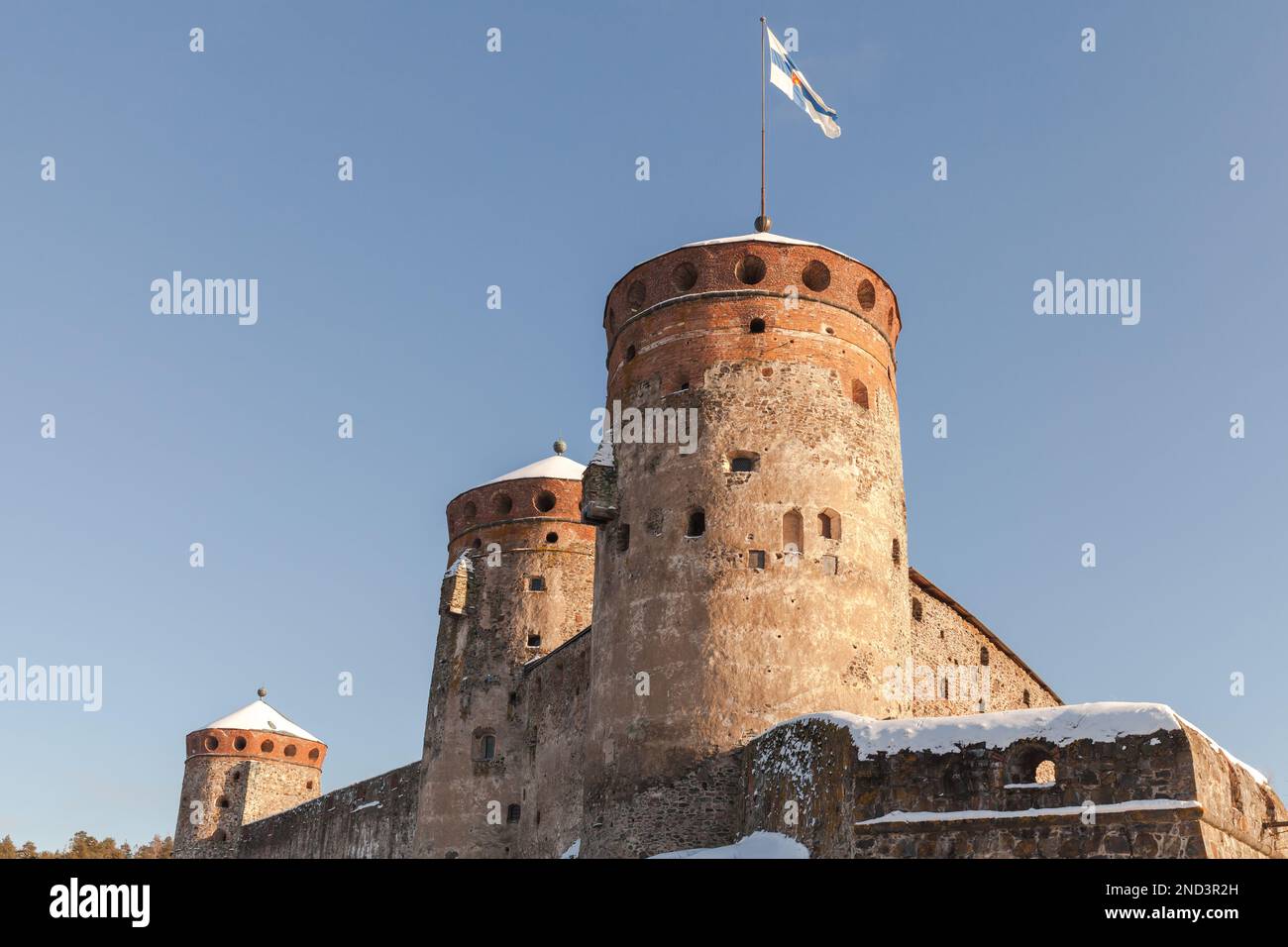 Olavinlinna is under blue sky on a sunny winter day. It is a 15th-century three-tower castle located in Savonlinna, Finland. The fortress was founded Stock Photo