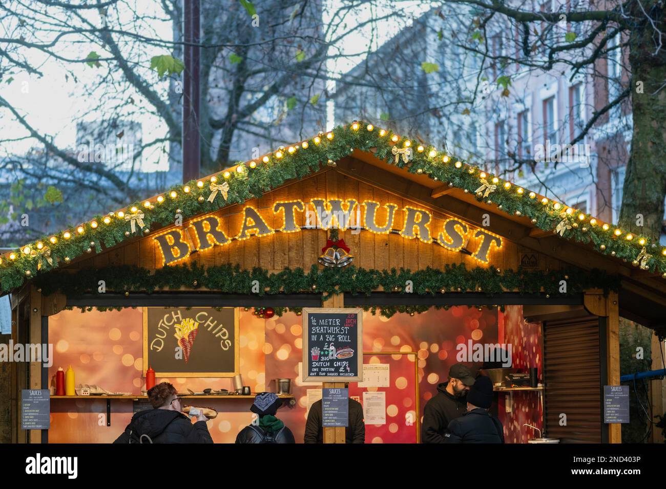 Closeup of illuminated sign of a bratwurst stall in a wooden alpine style chalet at the Manchester Christmas Markets. Manchester. UK Stock Photo