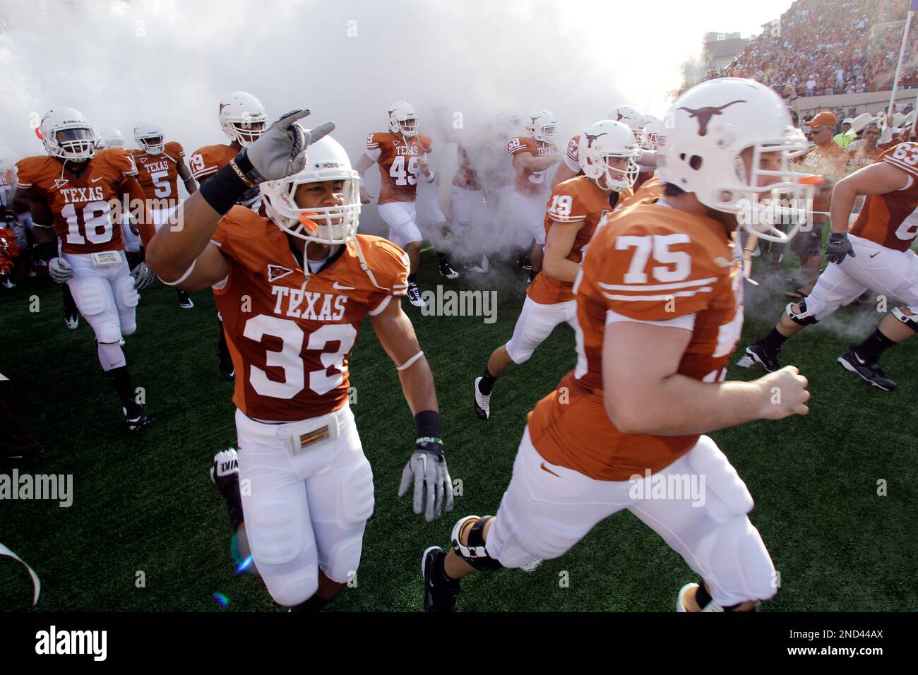 Texas' Jordan Hicks (33) and Steve Moore (75) take the field with