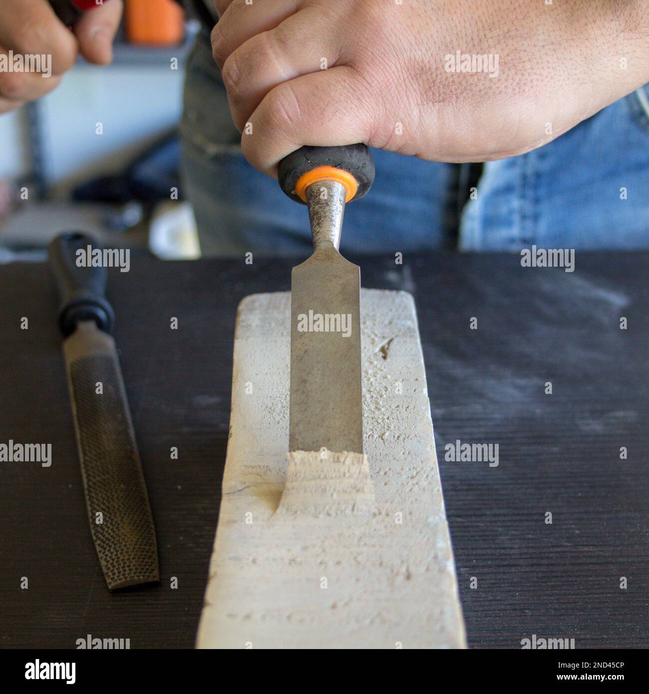 Image of a handyman craftsman's hands holding a carpenter's hammer and chisel while doing some work and carving on wood. DIY work in the laboratory. Stock Photo