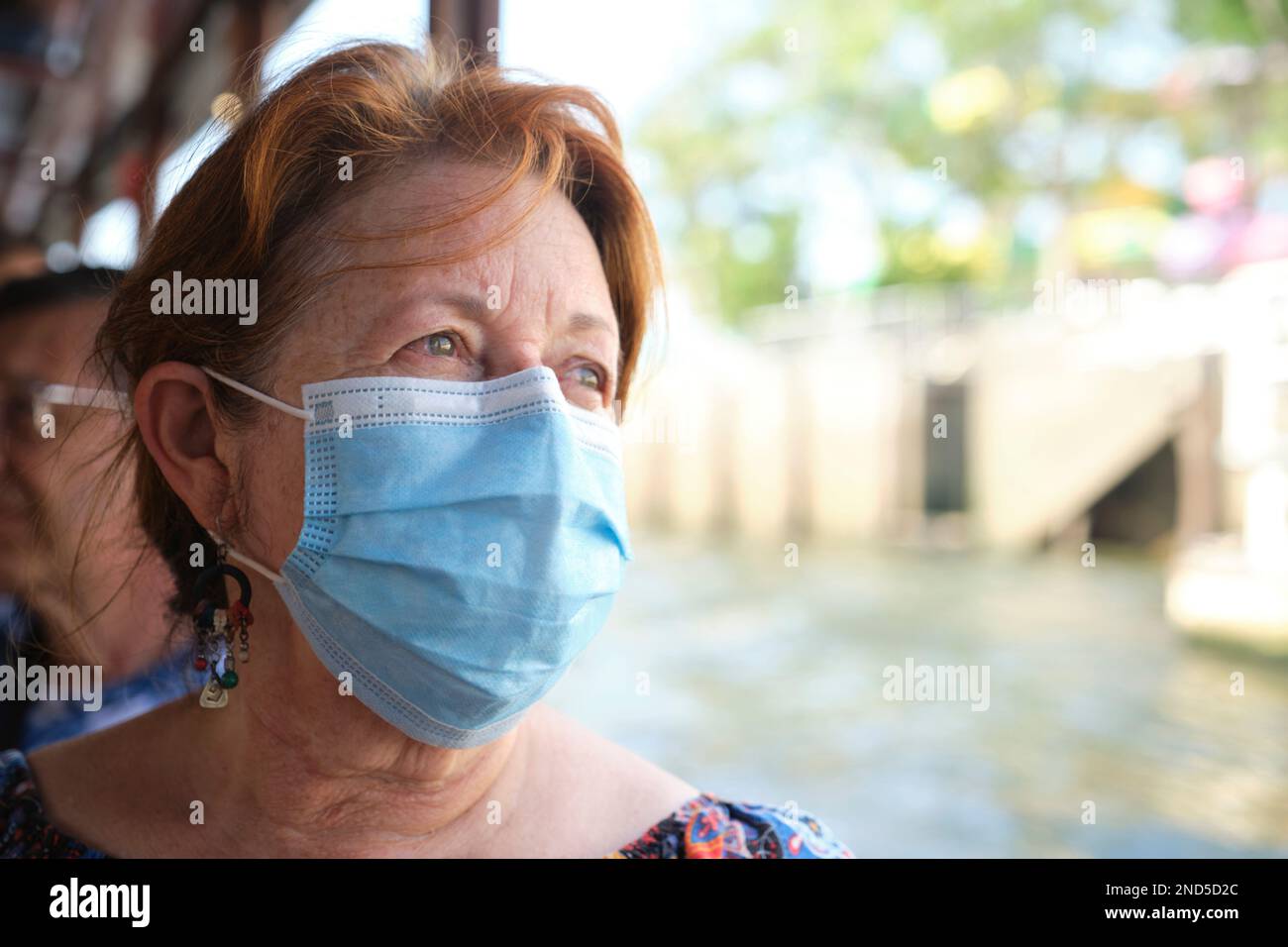 Mature Hispanic woman enjoying a sightseeing boat tour wearing a protective face mask to prevent the spread of diseases such as Covid19. Stock Photo