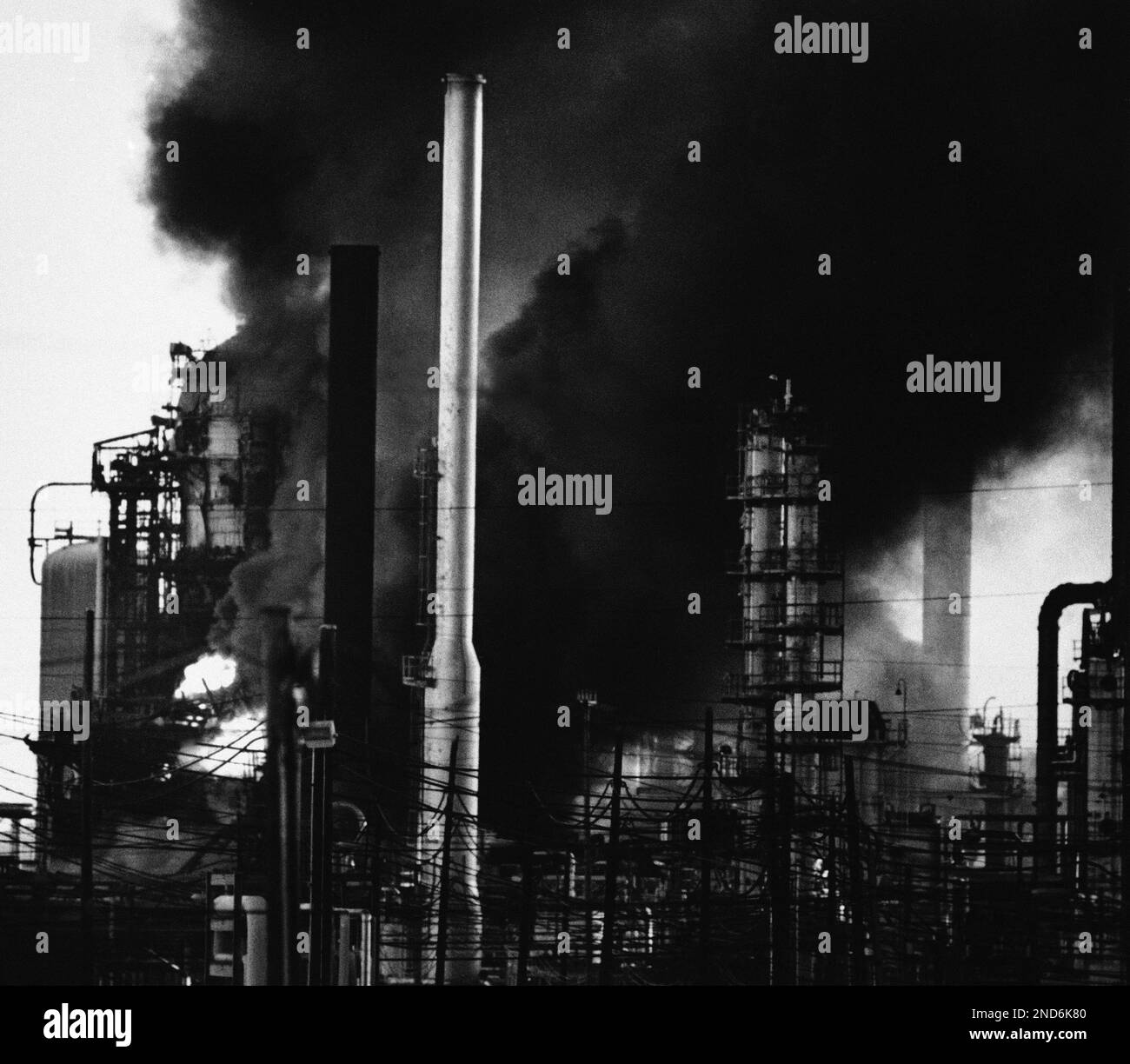 Flames and smoke outline the towers of the Shell Oil Co., refinery at
