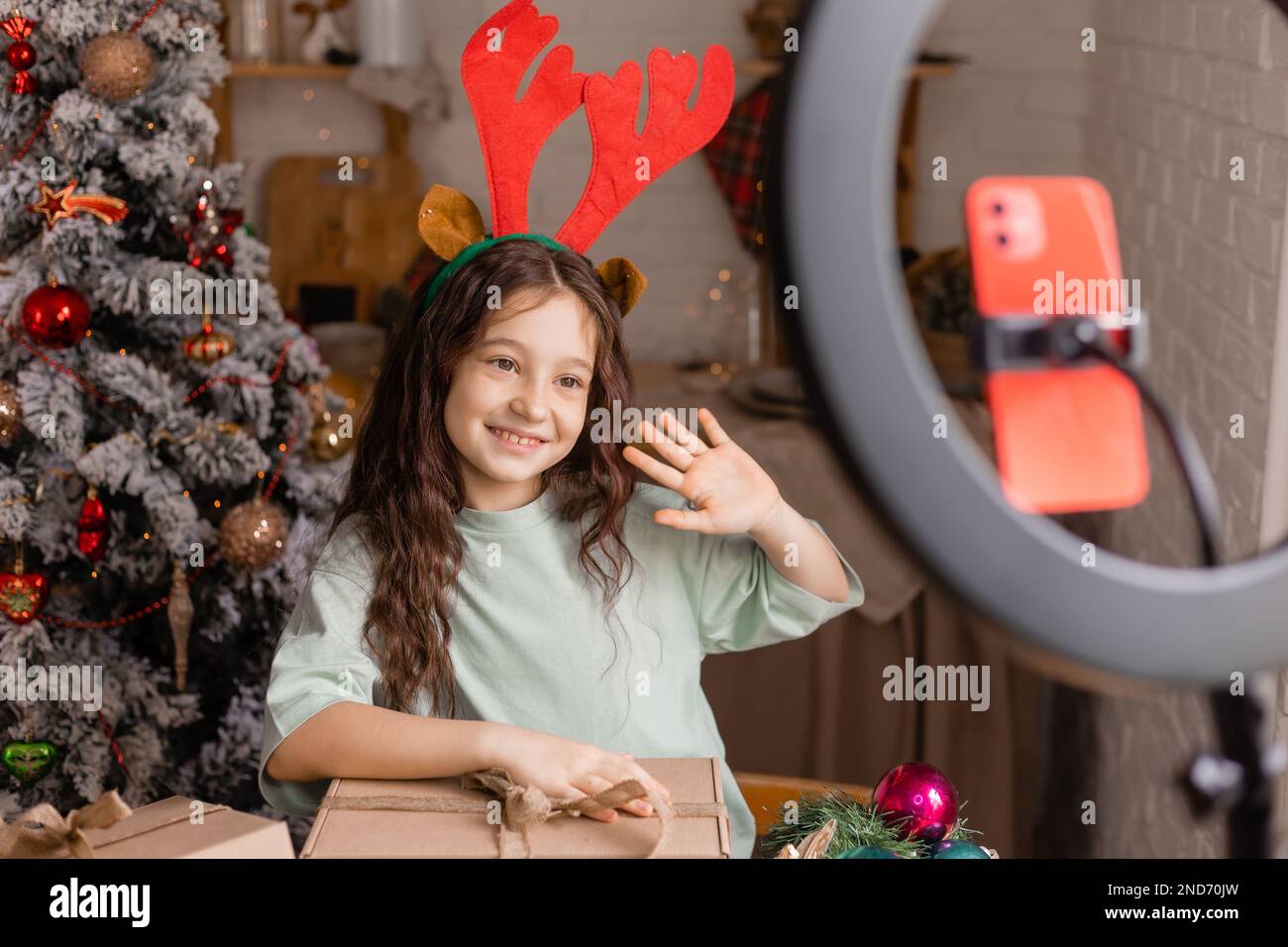 girl in reindeer horns conducts a Christmas live broadcast for social networks via a smartphone Stock Photo