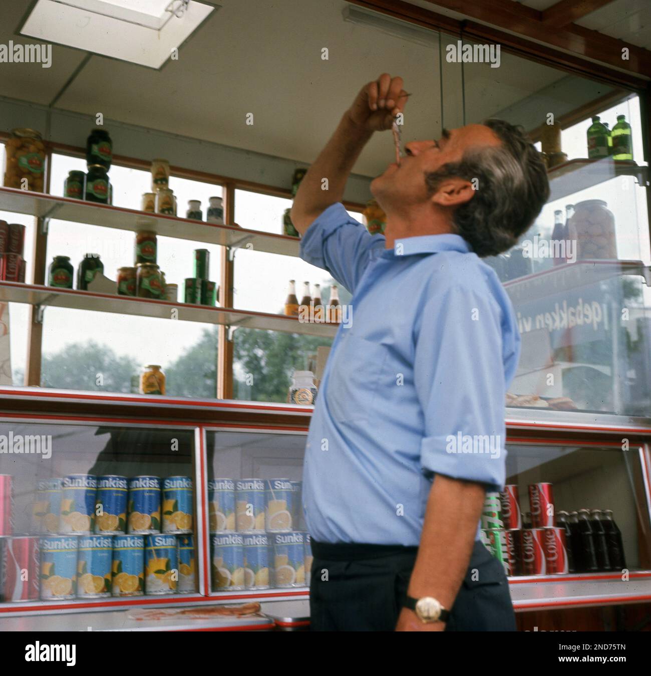 1960s, historical, a man at a snack kiosk eating fish, herring