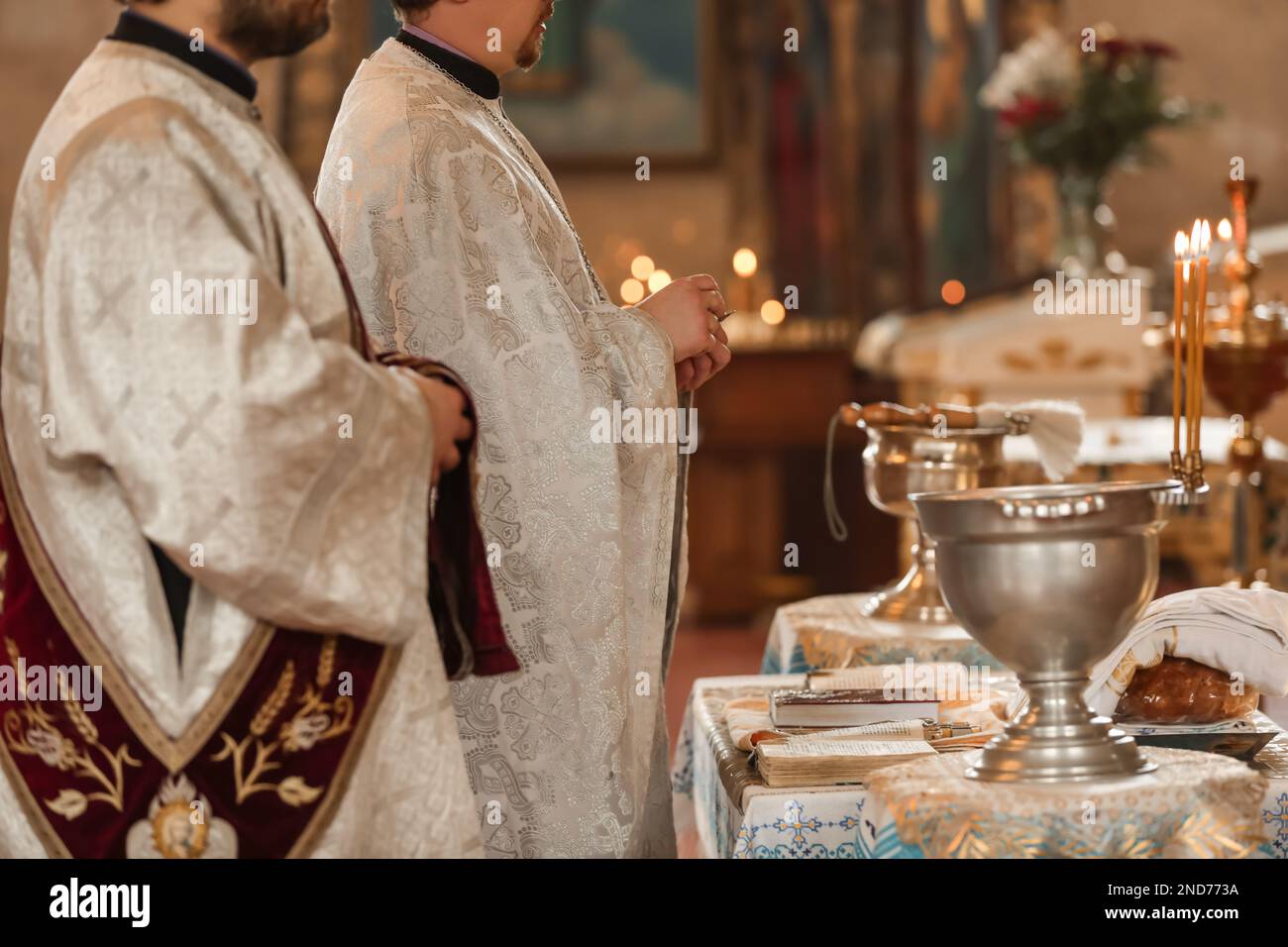 MYKOLAIV, UKRAINE - FEBRUARY 27, 2021: Deacon and priest conducting baptism ceremony in Kasperovskaya icon of Mother of God cathedral, closeup Stock Photo