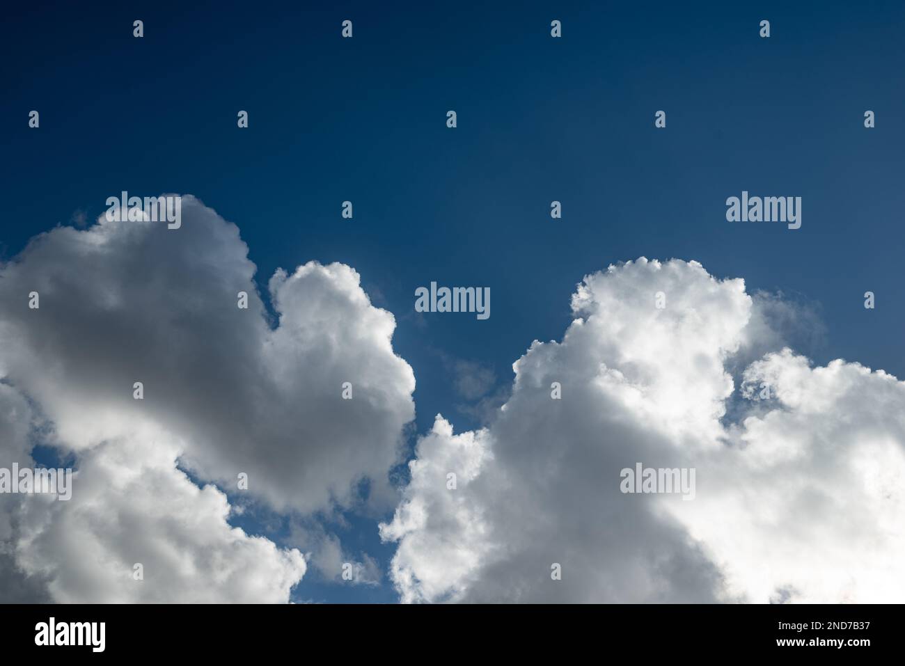 Sunlit cumulus clouds on blue sky background Stock Photo