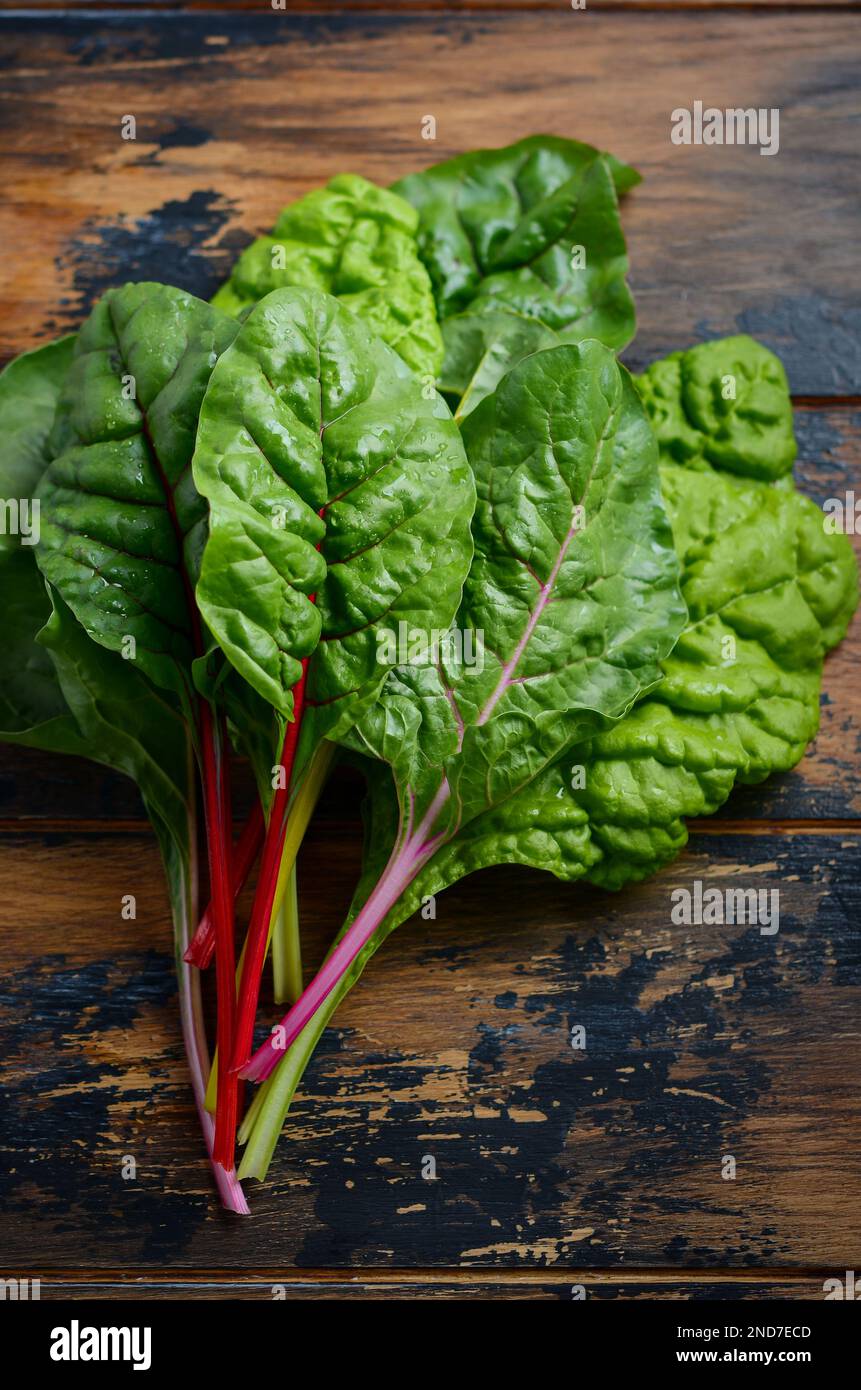 Fresh colorful chard leaves on old rustic wooden background. Stock Photo