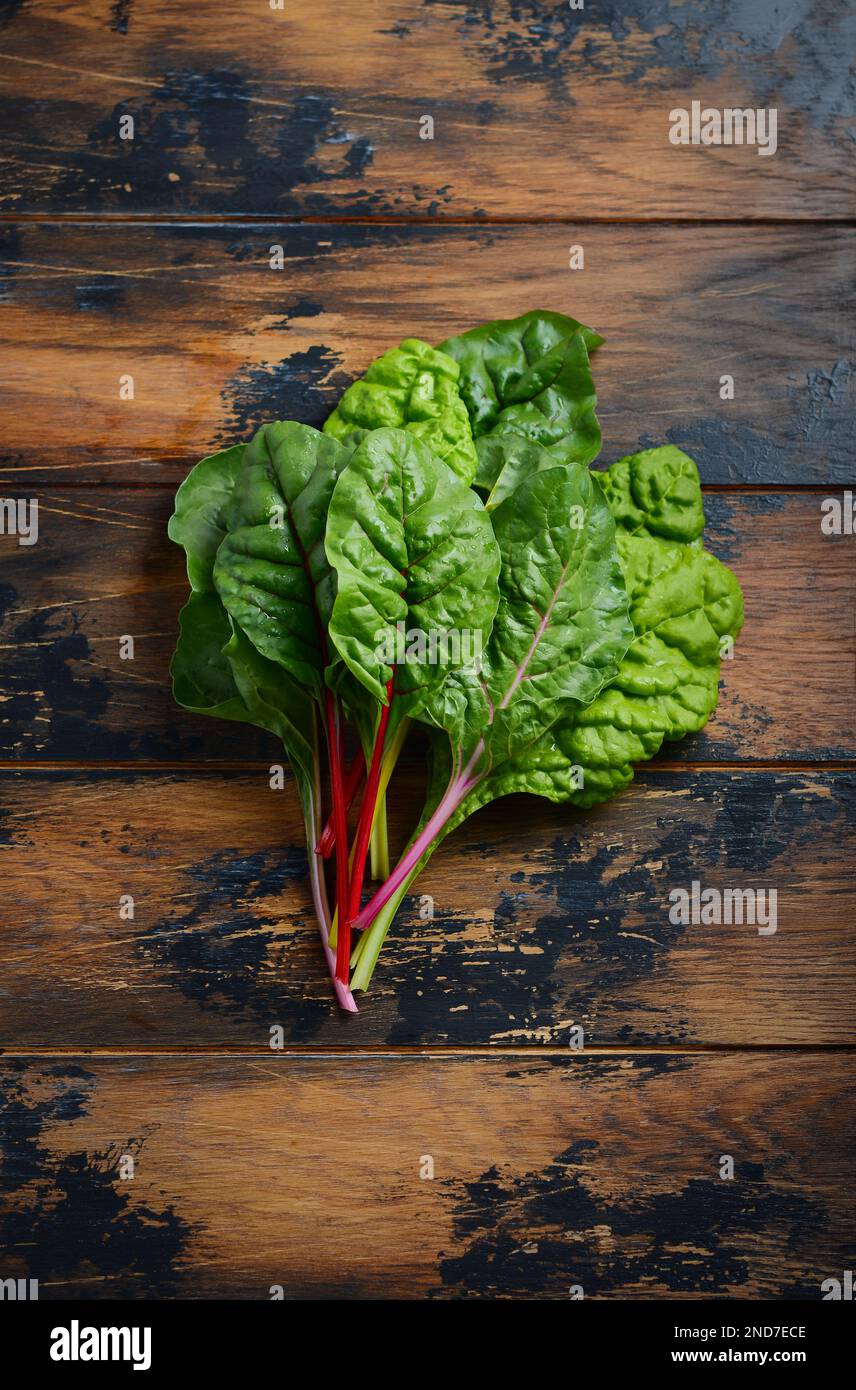 Fresh colorful chard leaves on old rustic wooden background. Stock Photo