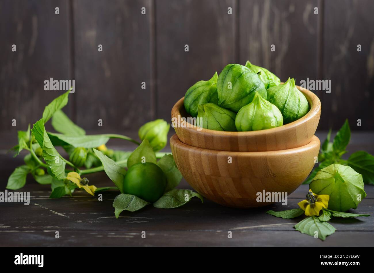 Fresh organic green tomatillos (Physalis philadelphica) with a husk on rustic wooden table. Stock Photo