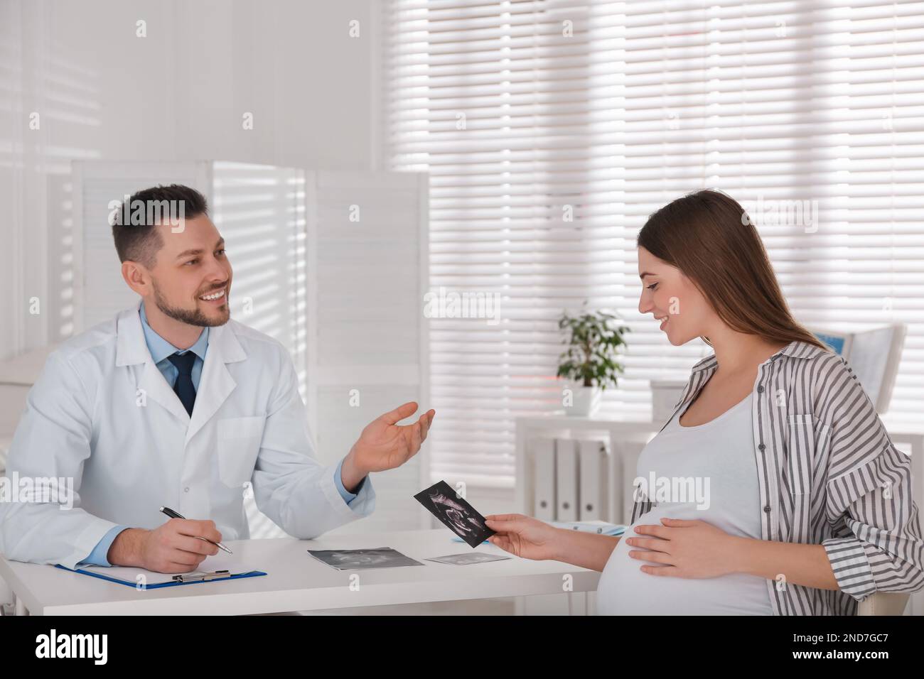 Pregnant woman with ultrasound picture at doctor's appointment in