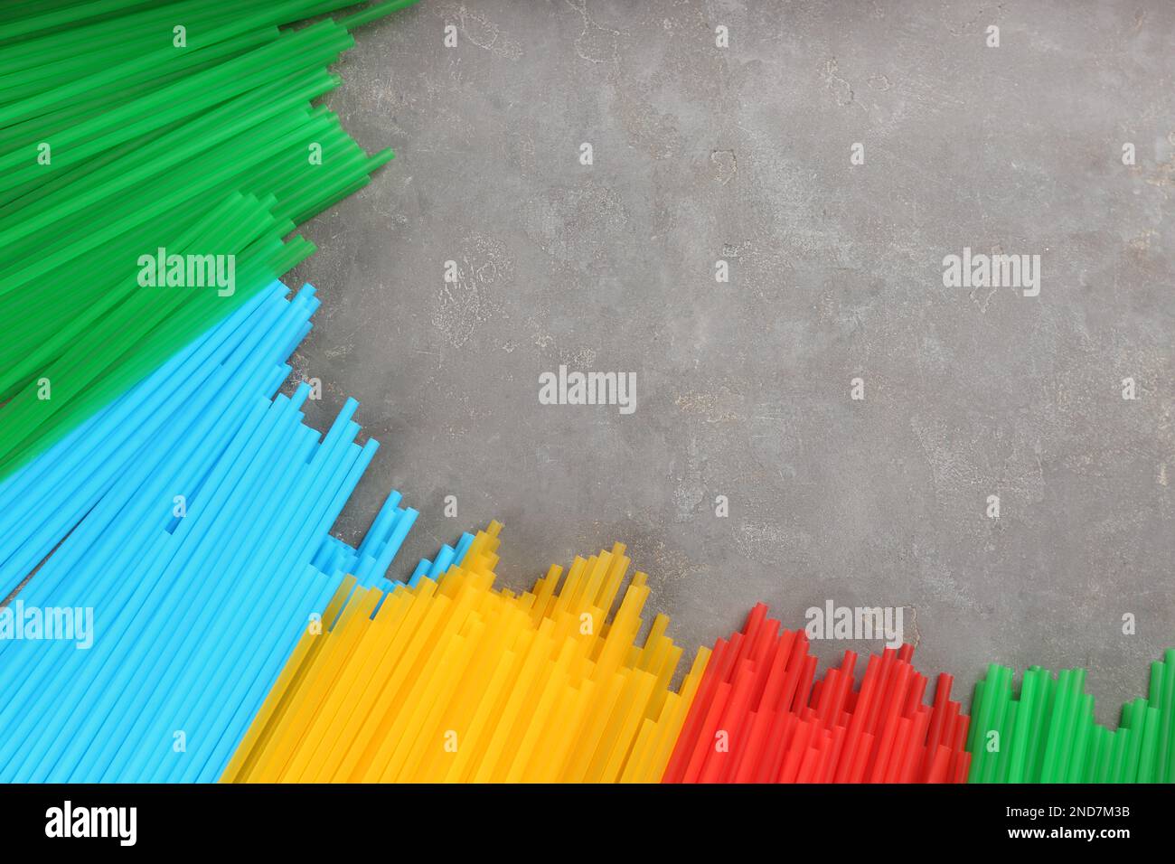 Colorful plastic drinking straws on grey stone table, flat lay. Space for text Stock Photo