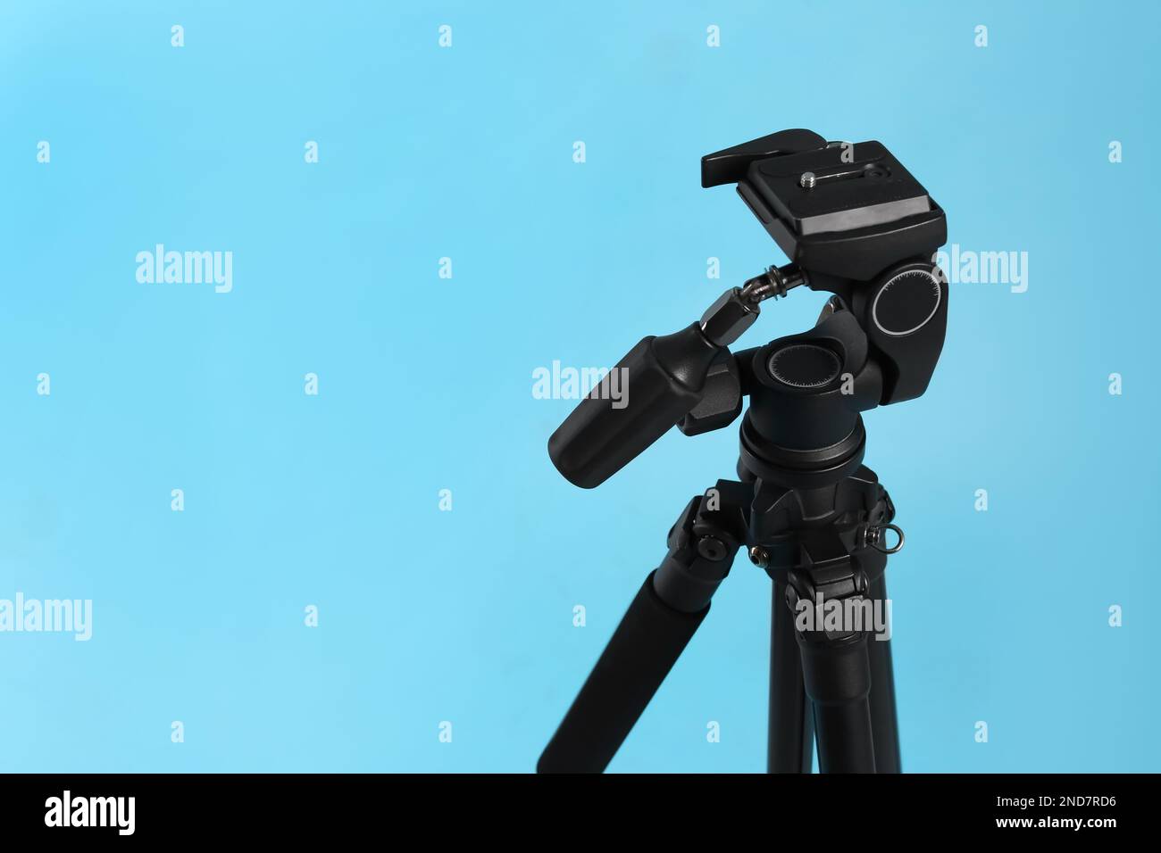 Modern tripod on light blue background. Space for text Stock Photo - Alamy
