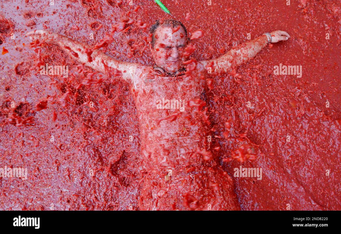 A man plays with tomato pulp during the annual "tomatina" tomato fight fiesta in the village of Bunol, near Valencia, Spain, Wednesday, Aug. 25, 2010. Bunol's town hall estimated more than 40,000 people, some from as far away as Japan and Australia, took up arms Wednesday with 100 tons of tomatoes in the yearly food fight known as the 'Tomatina' now in its 65th year. (AP Photo/Alberto Saiz) Stock Photo