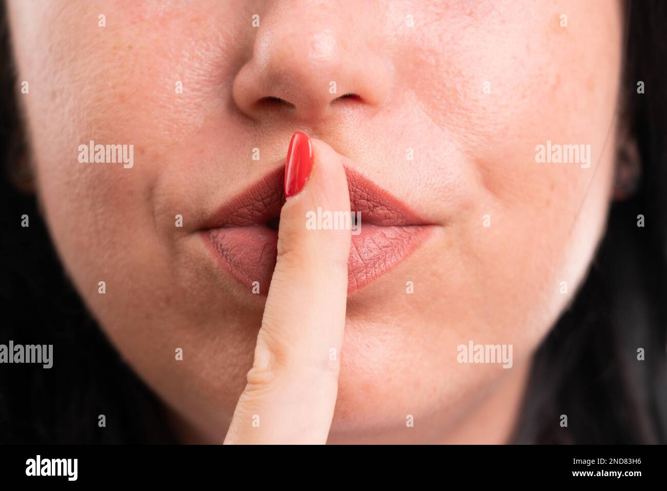 Close-up of shush silence gesture with index finger over mouth made by entrepreneur business woman as corporate professional secret concept isolated o Stock Photo