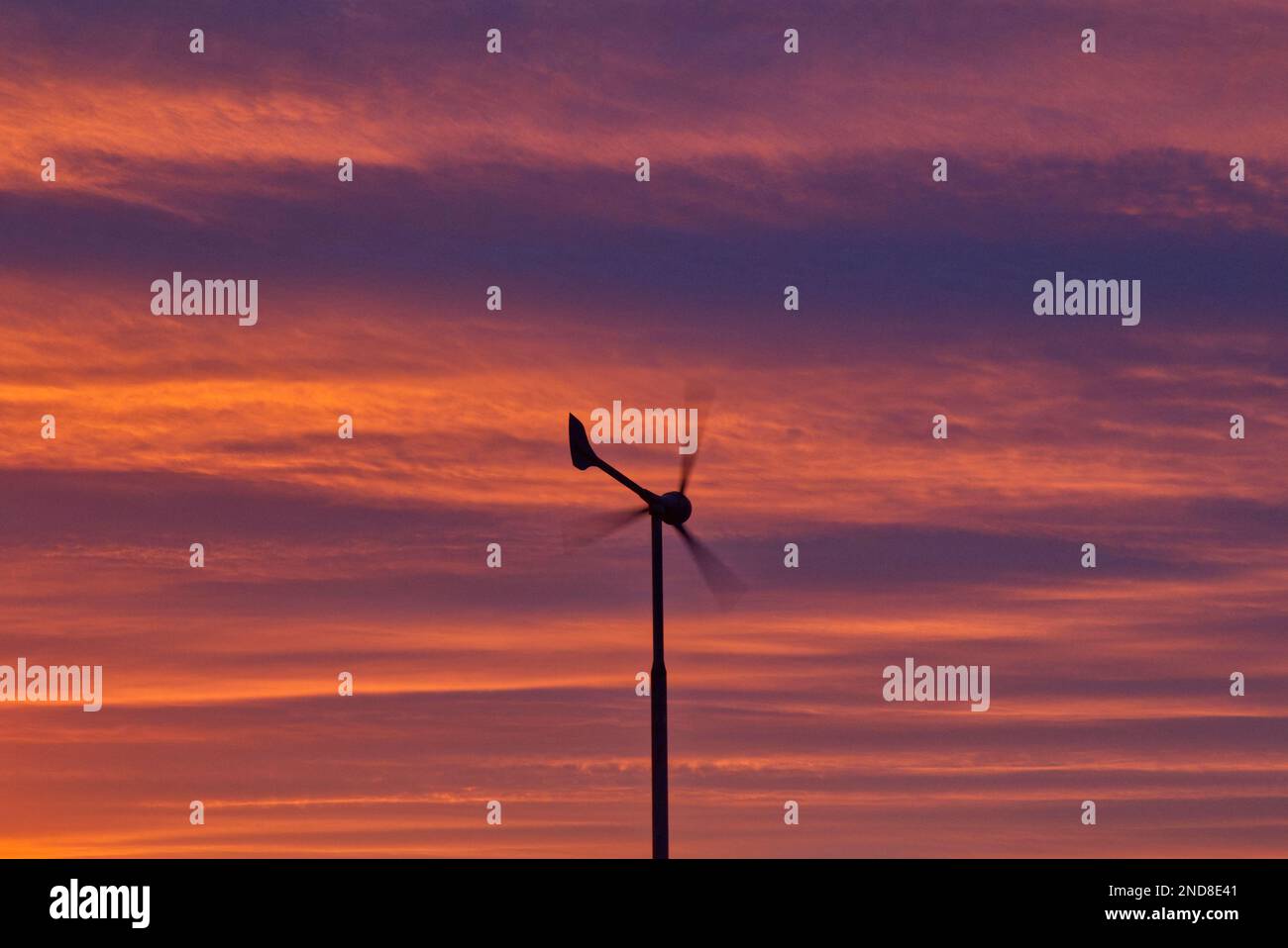 Wind turbine silhouetted against a red sky Stock Photo
