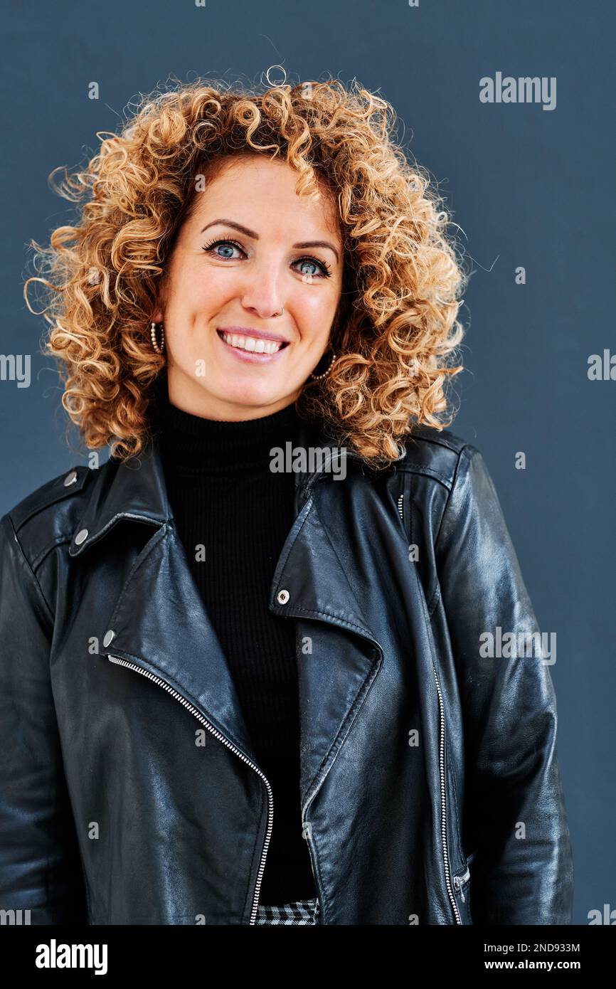 Portrait of a woman with curly hair looking at camera and smiling. Stock Photo