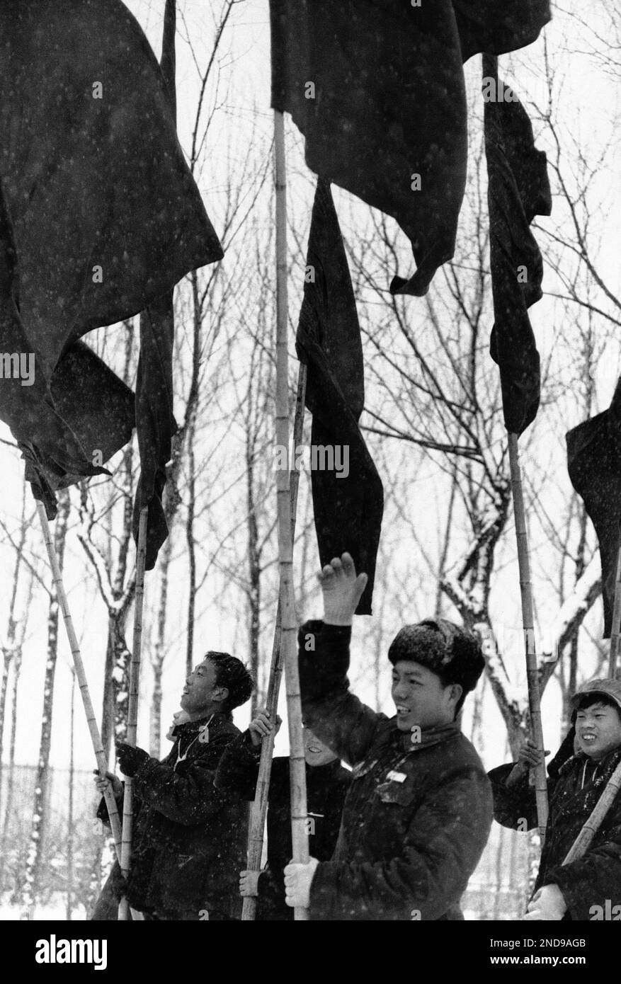 Red guards on parade carrying flags and waving during snow fall in