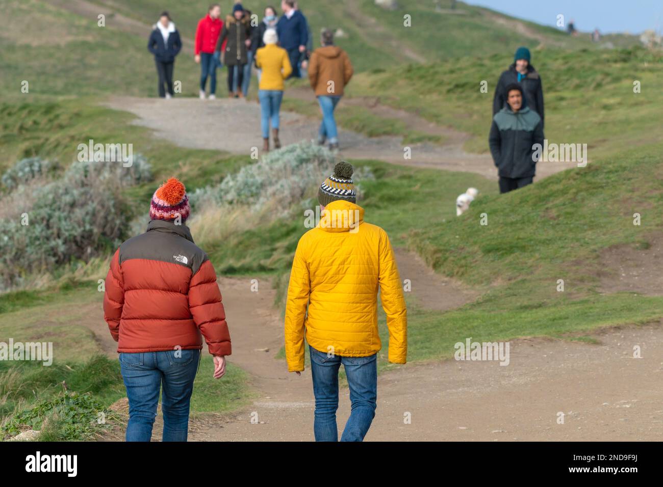 Walkers on the coast path to Towan Head in Newquay in Cornwall in the UK. Stock Photo