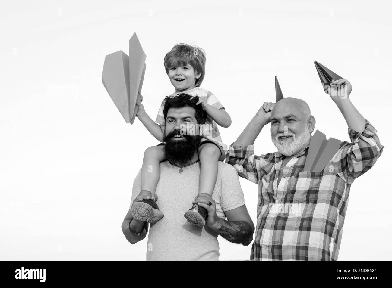 Happy smiling boy on shoulder dad looking at camera. Three different generations ages: grandfather father and child son together. Stock Photo